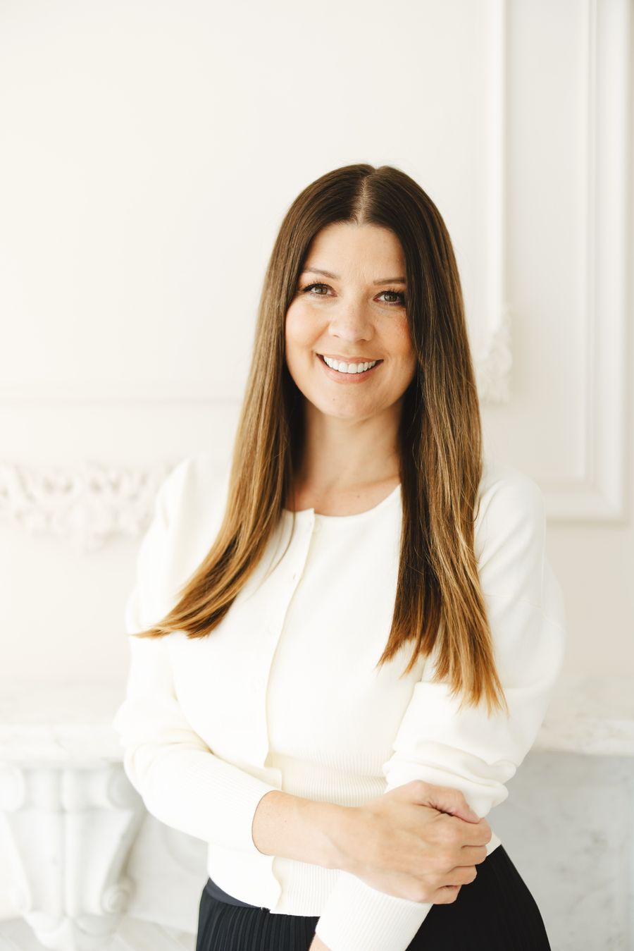 Dr. Stephanie Helfand smiling, standing in a bright white room, wearing a cream cardigan.